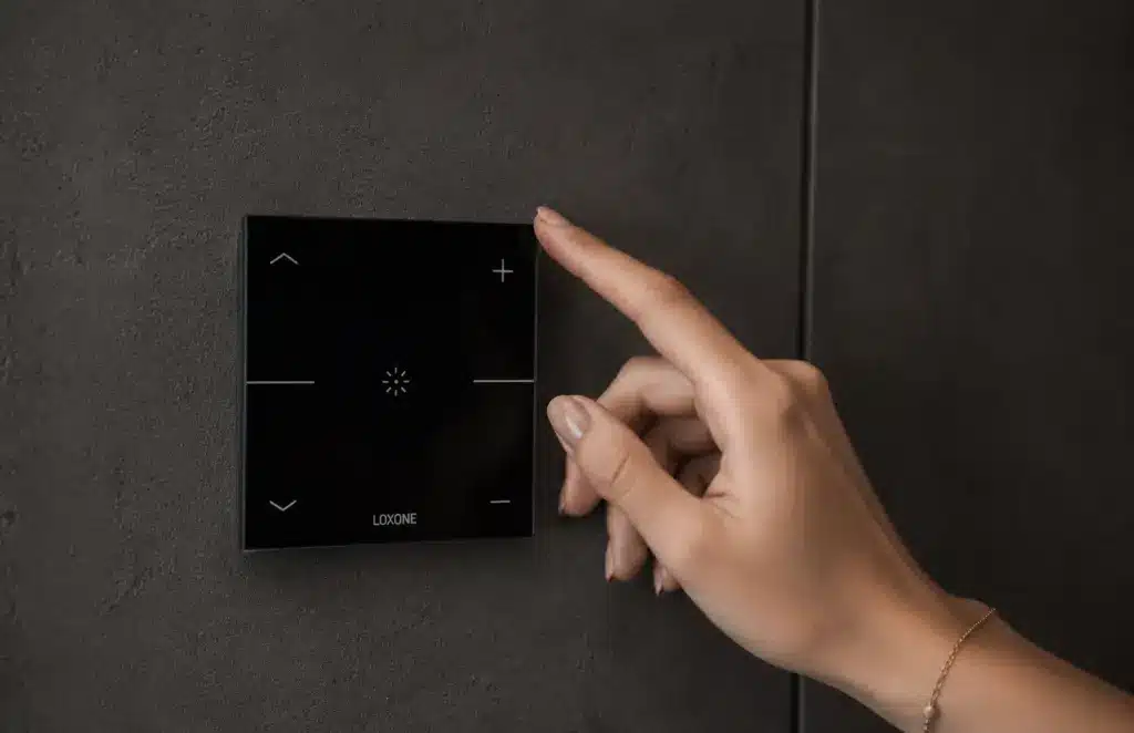 Ženská ruka ovláda panel Loxone Touch Pure